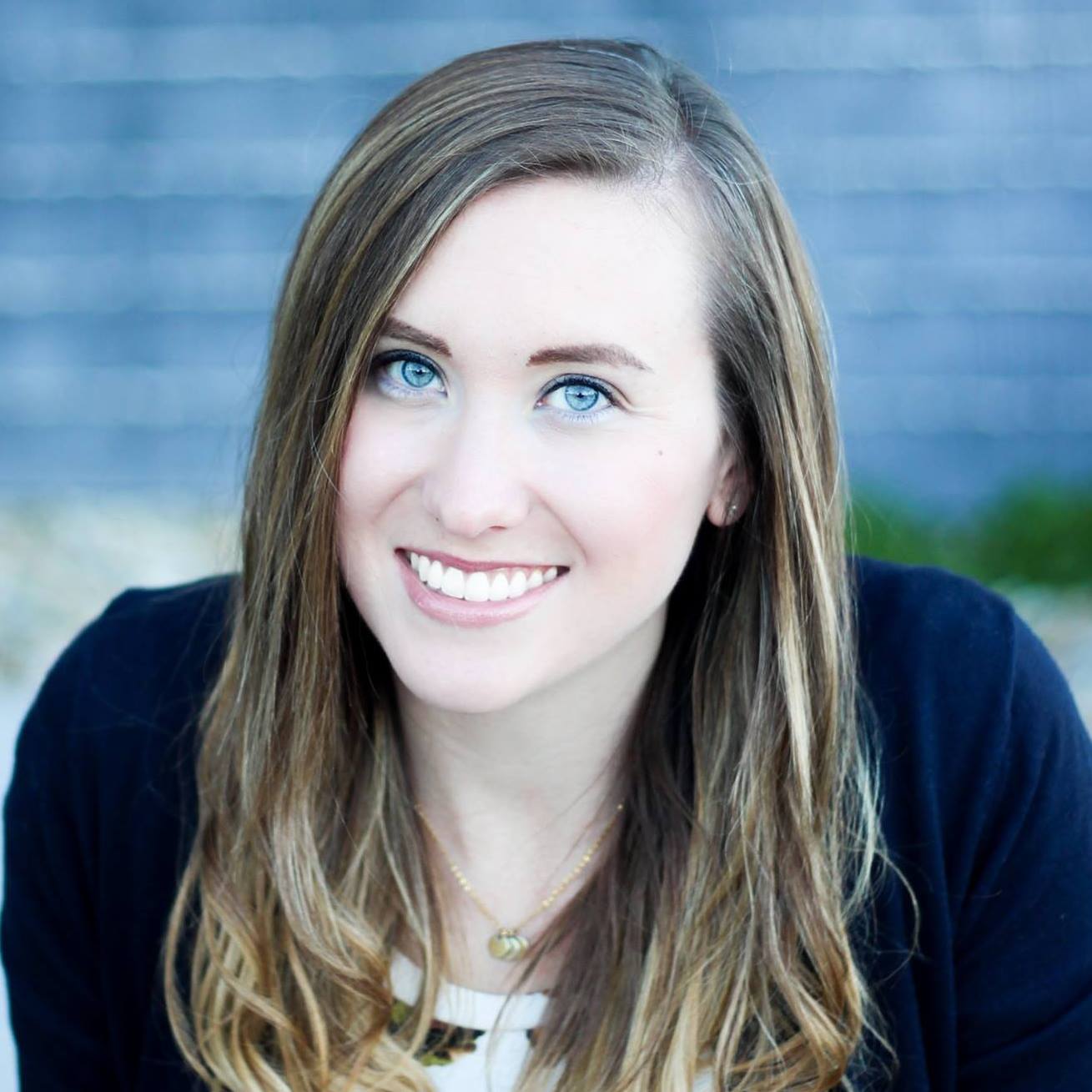 A woman with long hair and blue eyes is smiling for the camera.