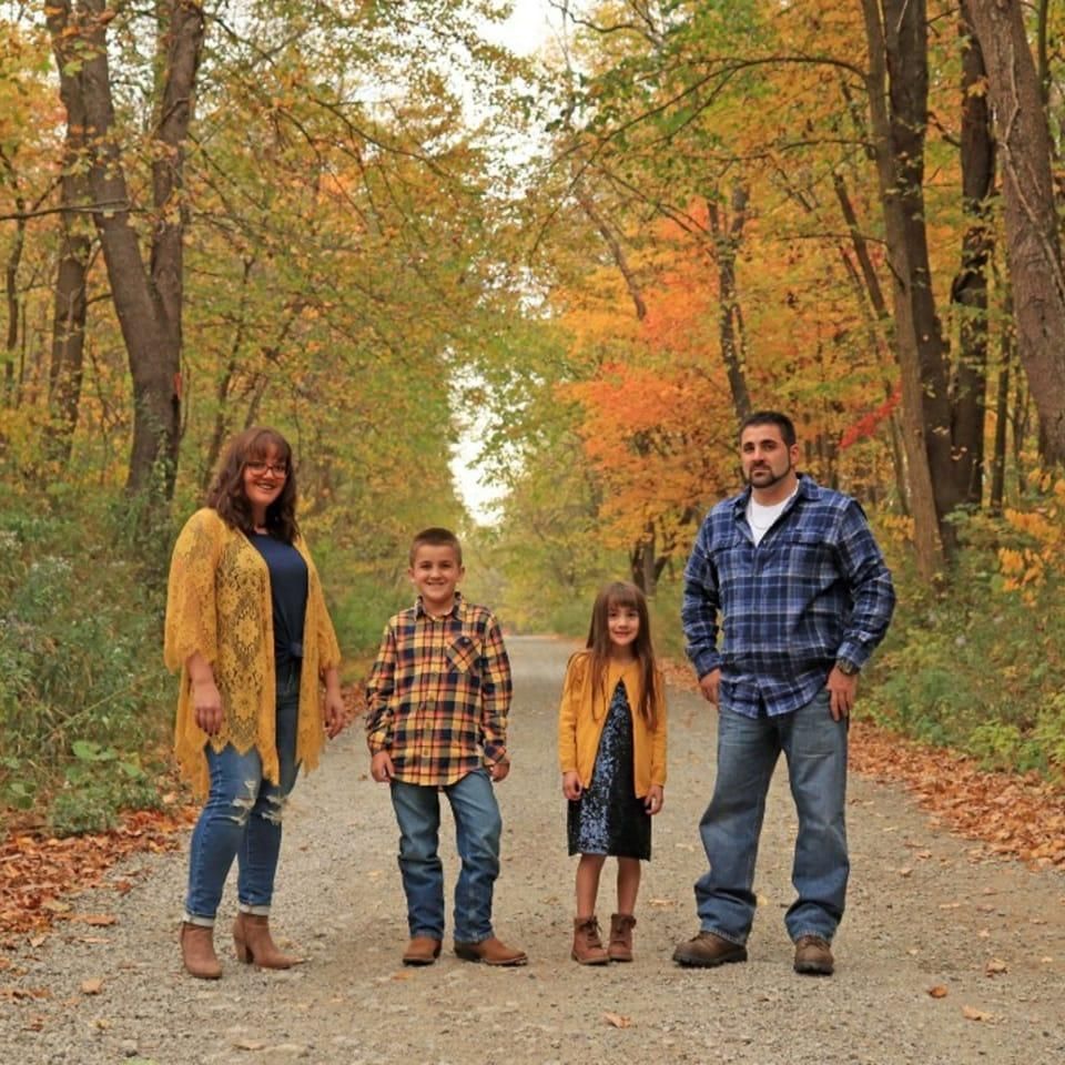 A family standing on a dirt road in the woods