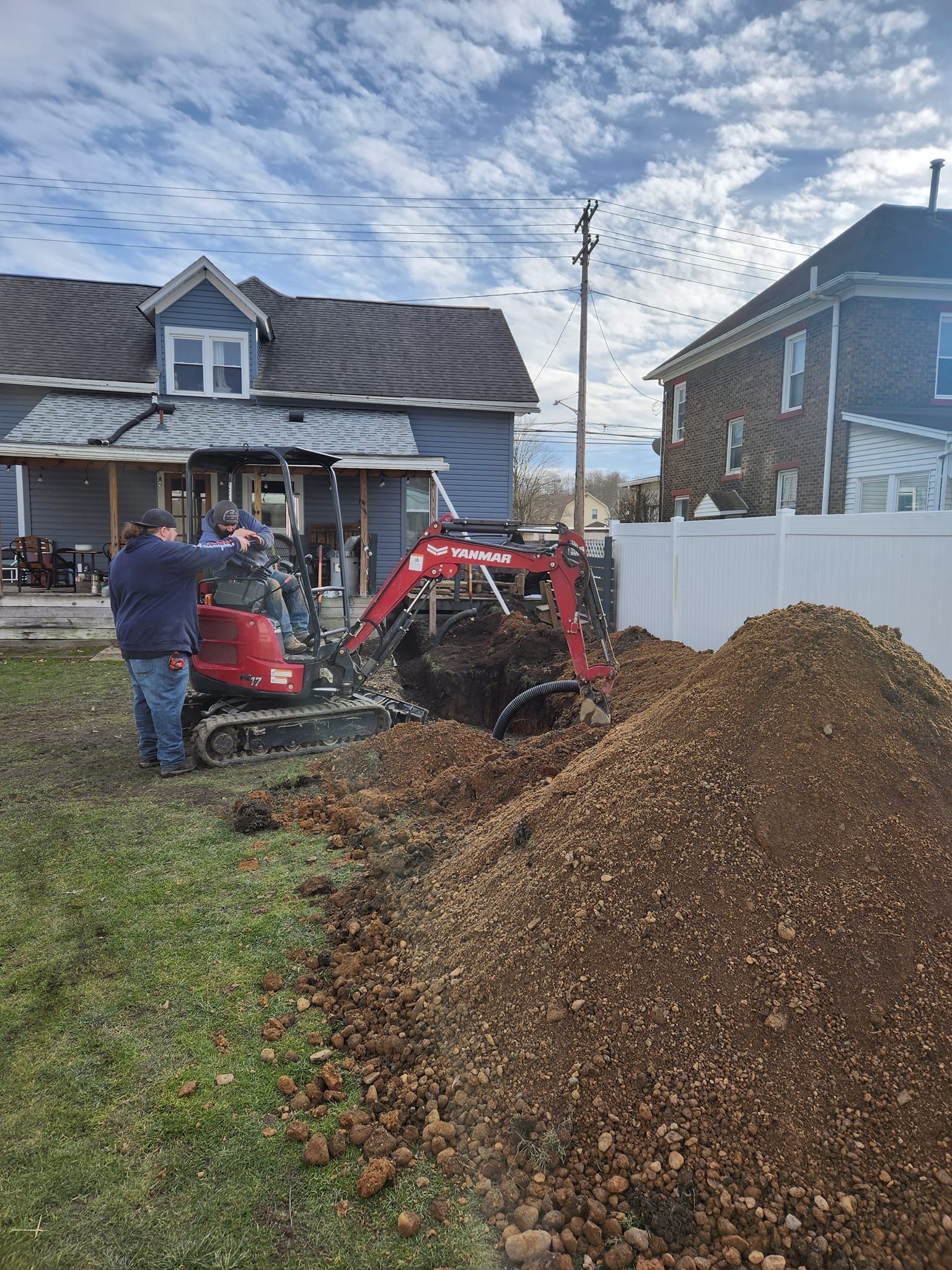 A man is standing next to a pile of dirt in front of a house.