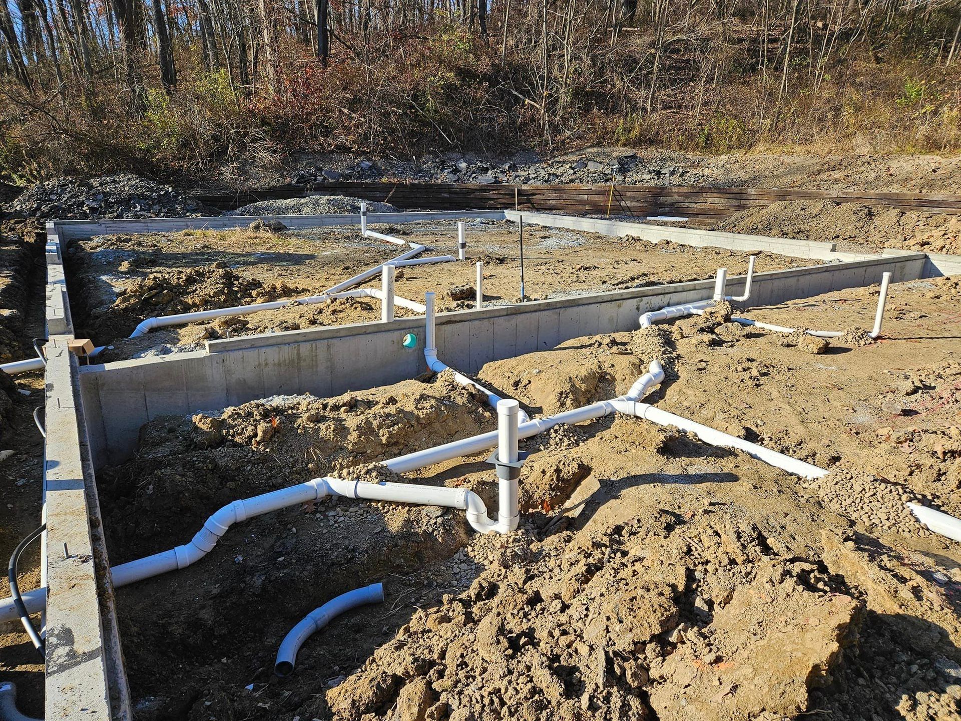 A bunch of pipes are laying in the dirt