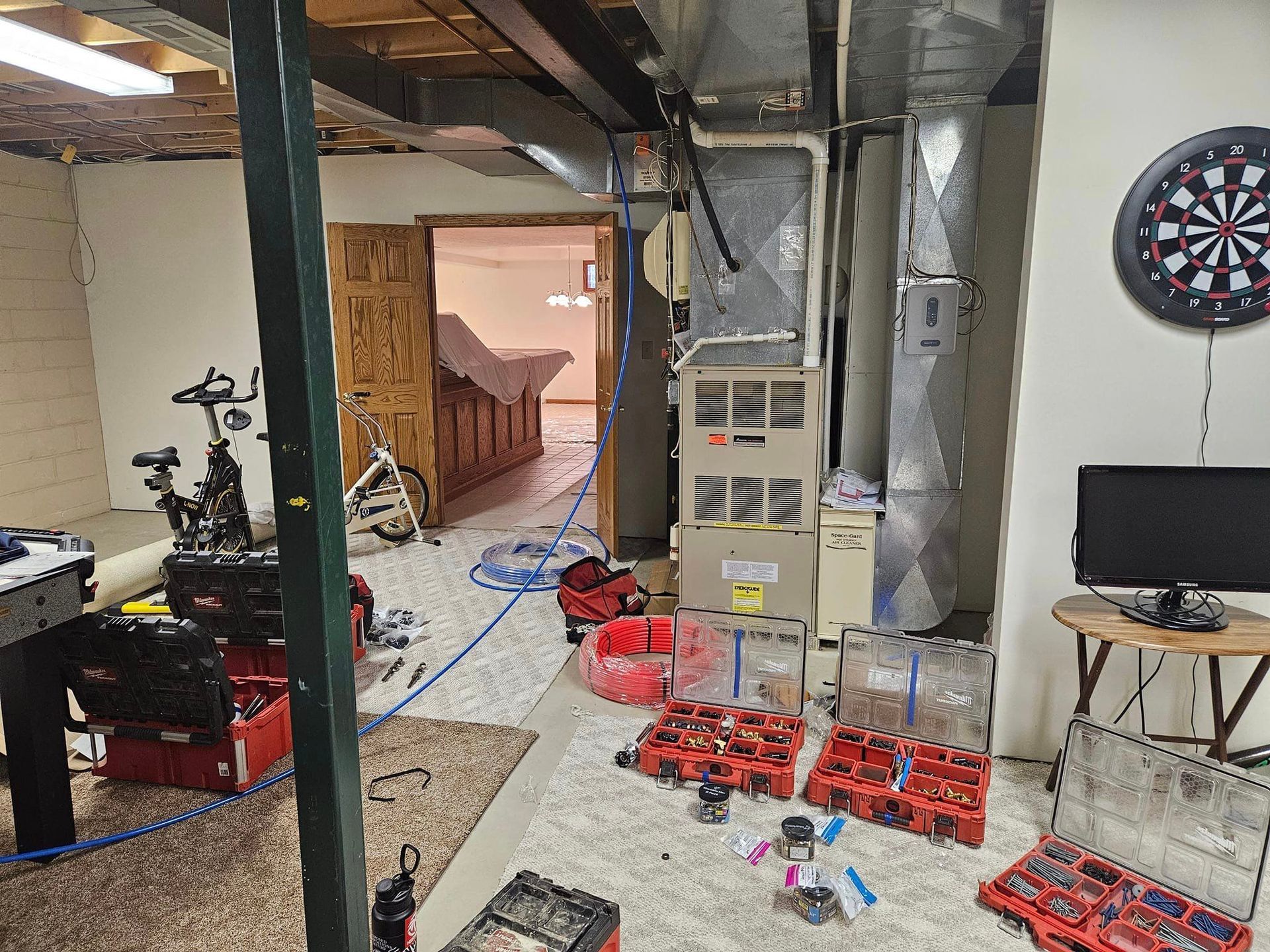 A basement with a dart board on the wall and a lot of tools on the floor.