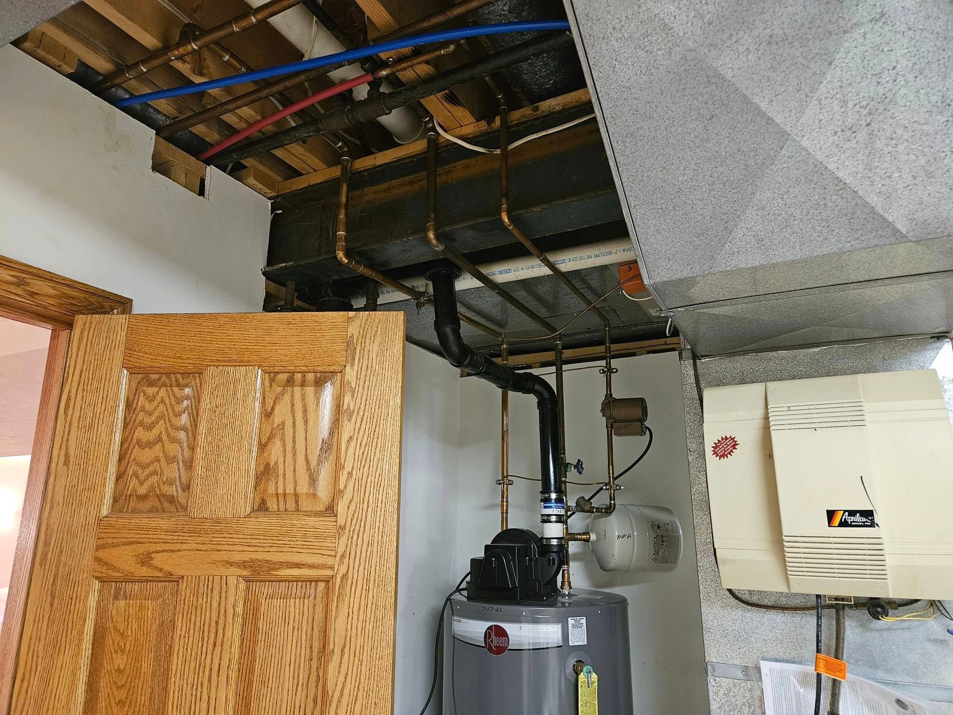 A room with a water heater and a wooden door