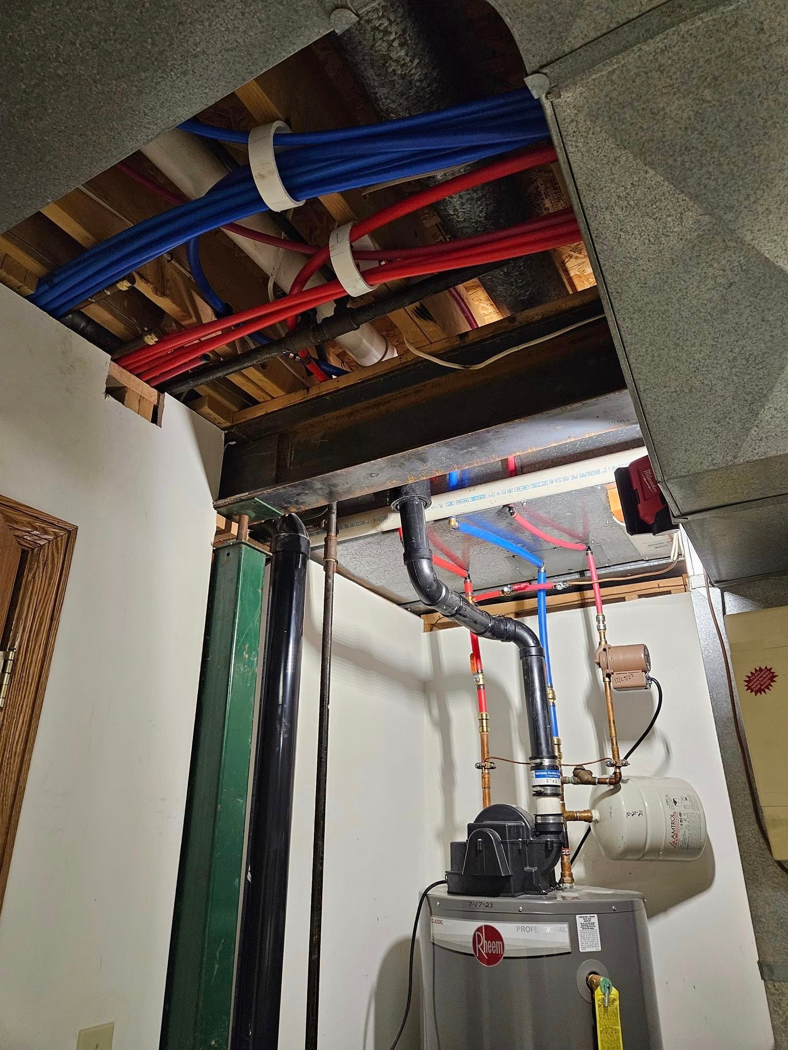 A room with a water heater and pipes hanging from the ceiling.