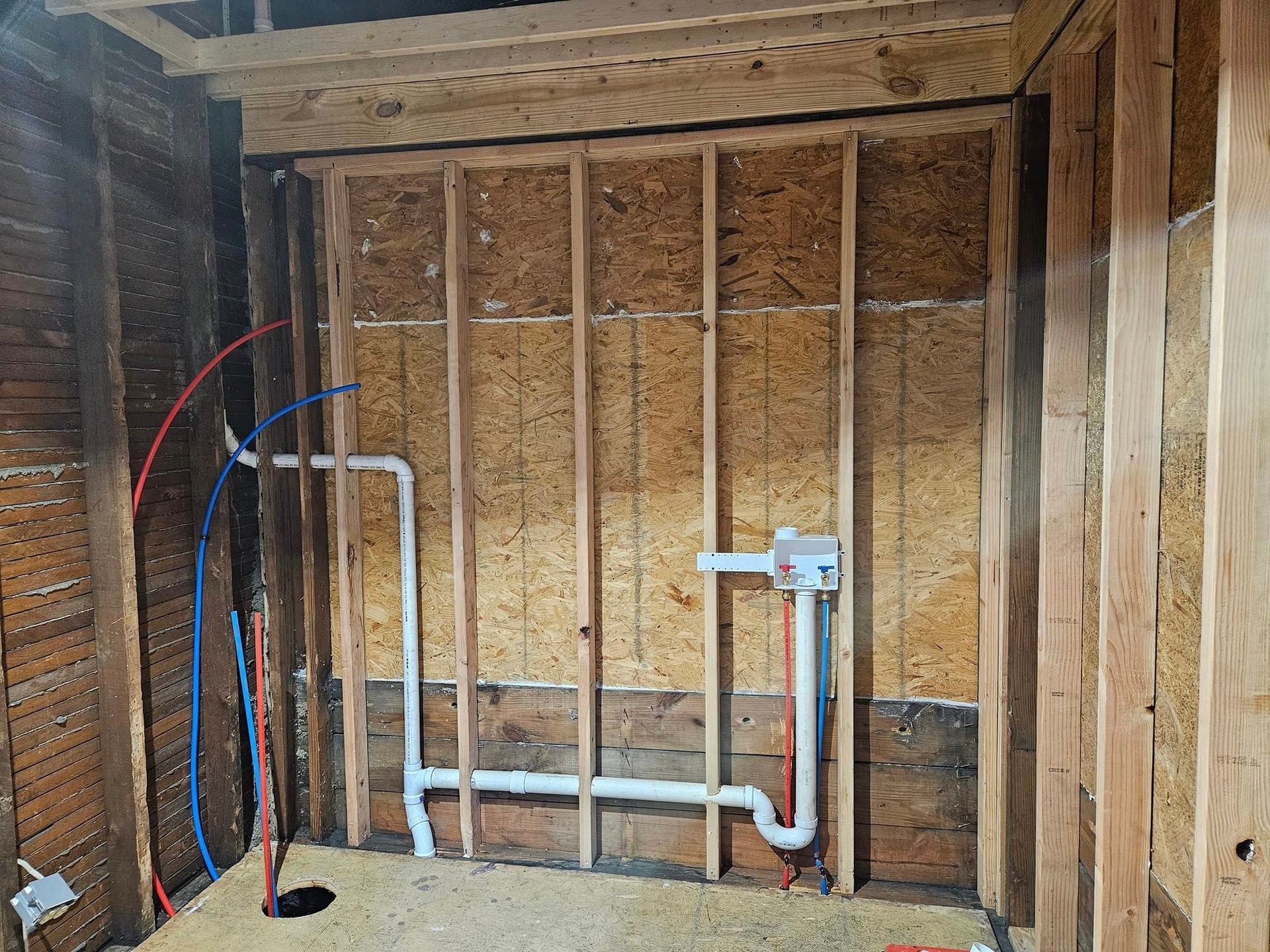 A bathroom under construction with pipes coming out of the wall.