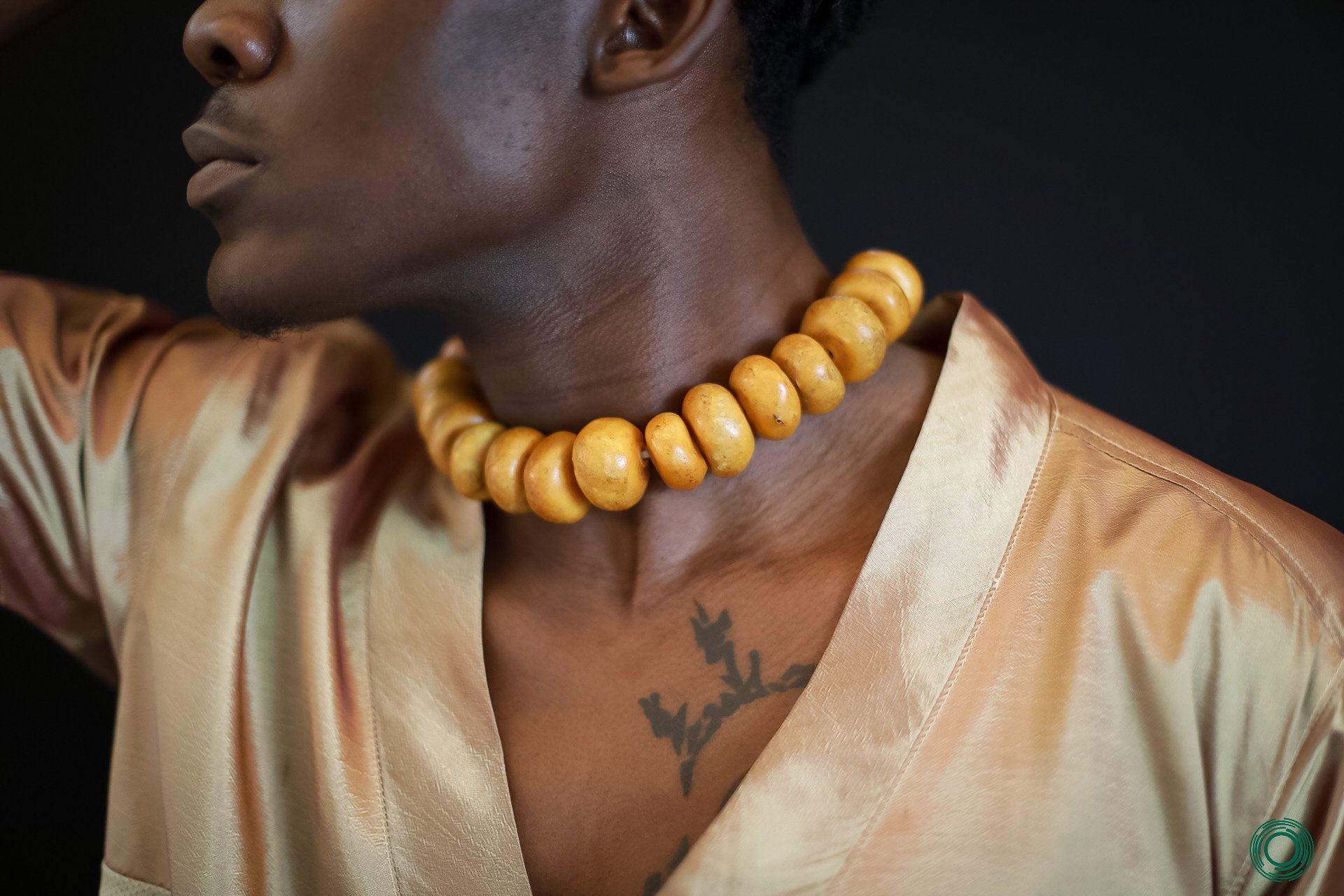 A man with a tattoo on his chest is wearing a choker necklace.