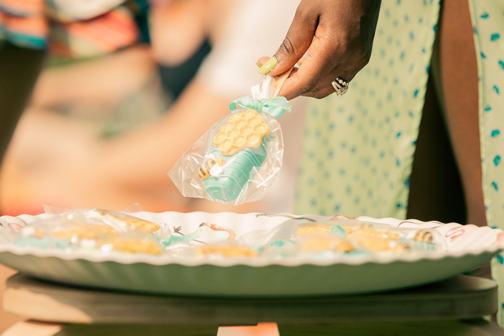 A person is holding a lollipop over a plate of cookies.