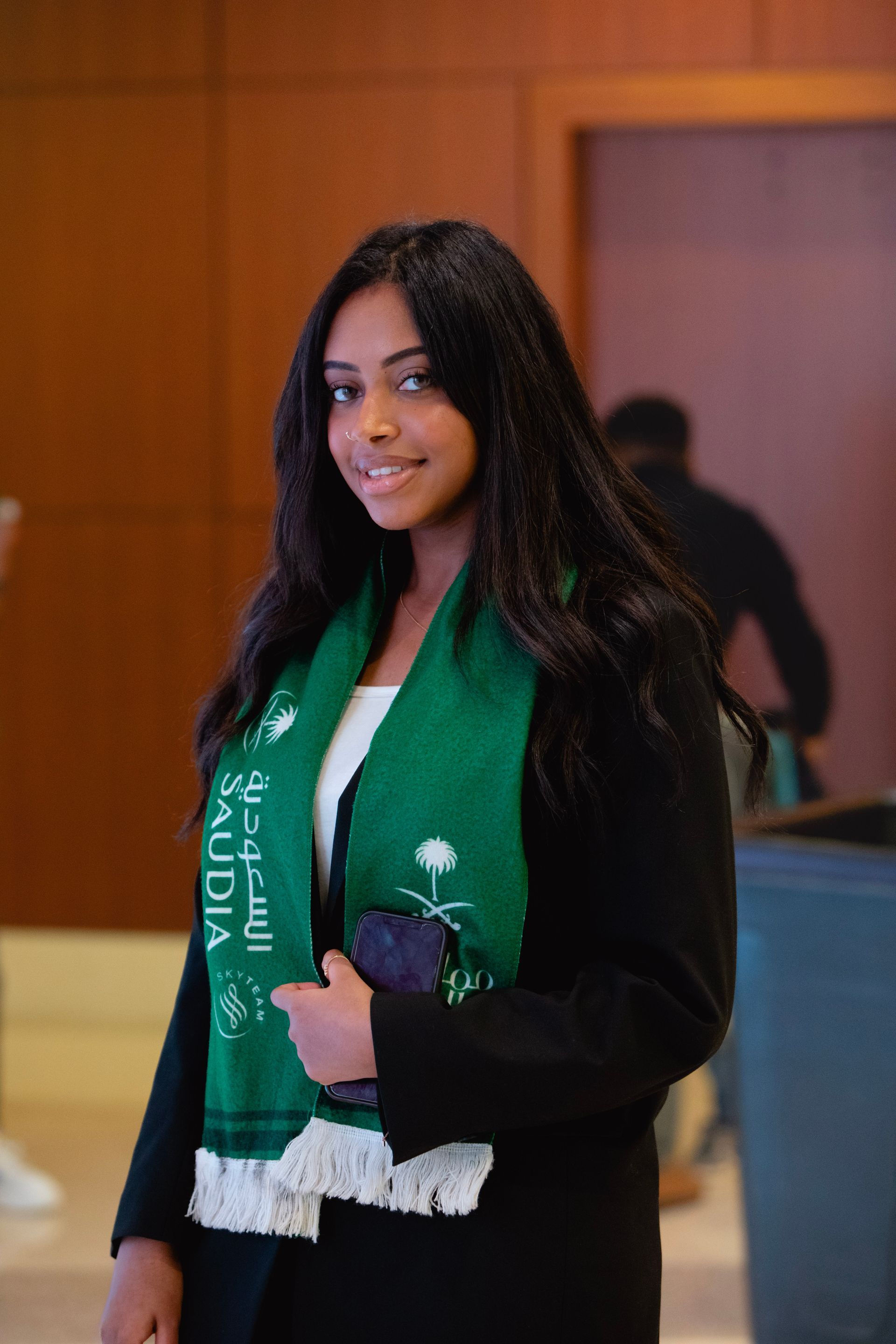 A woman wearing a green scarf that says saudia on it