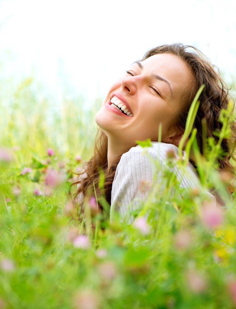 Beautiful Woman Lying in Meadow of Flowers — Colonic Healthcare in Rosslea, QLD