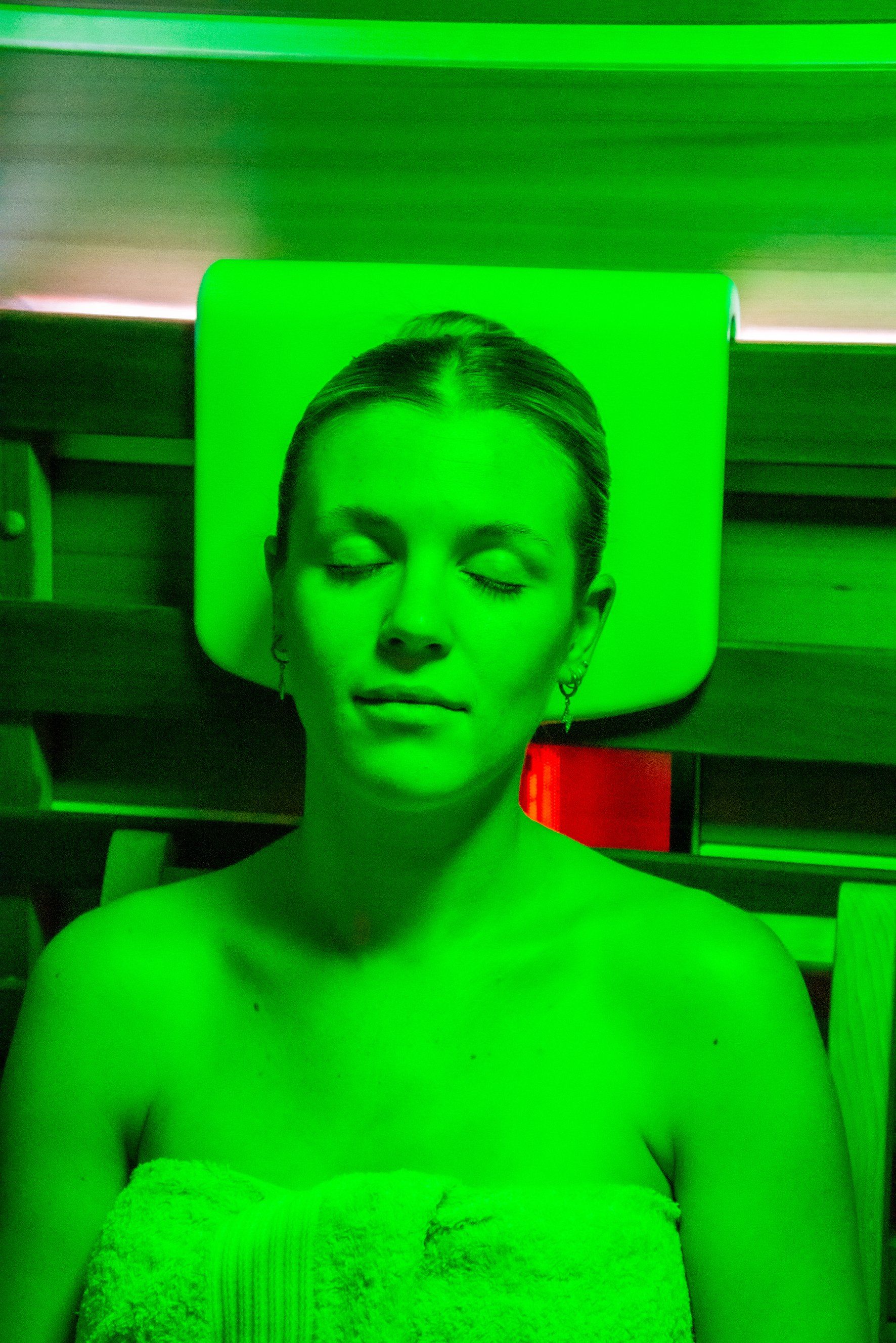 Woman Relaxing In Sauna With Green Light — Colonic Healthcare in Rosslea, QLD