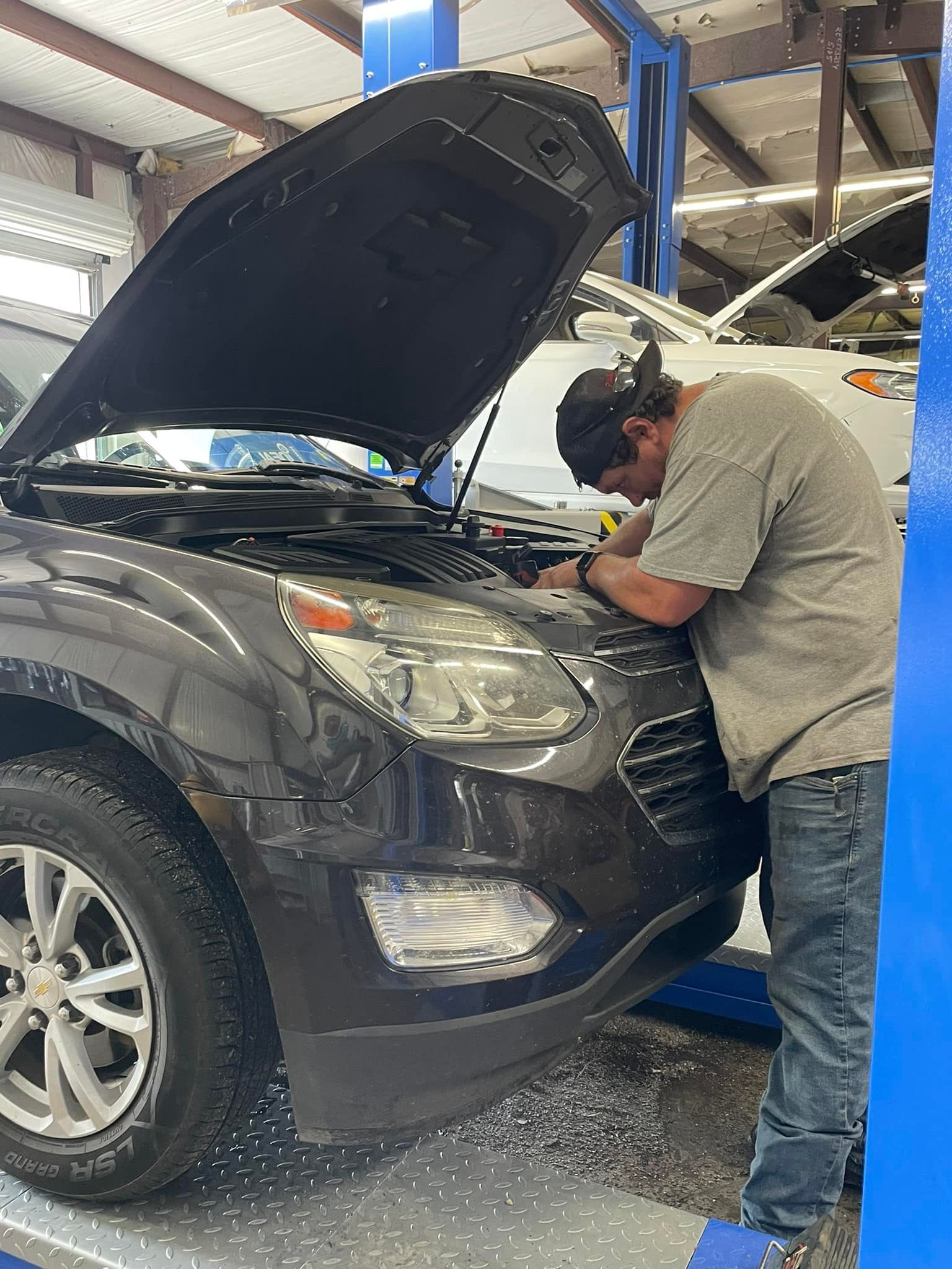 Mechanic Working Under the Open Hood of a Vehicle | Pauls Valley Automotive