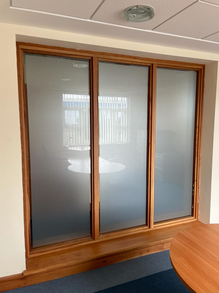 A room with three windows and a wooden table.