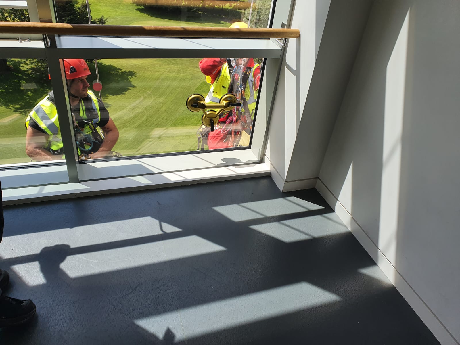 A man in a yellow vest is standing in front of a window