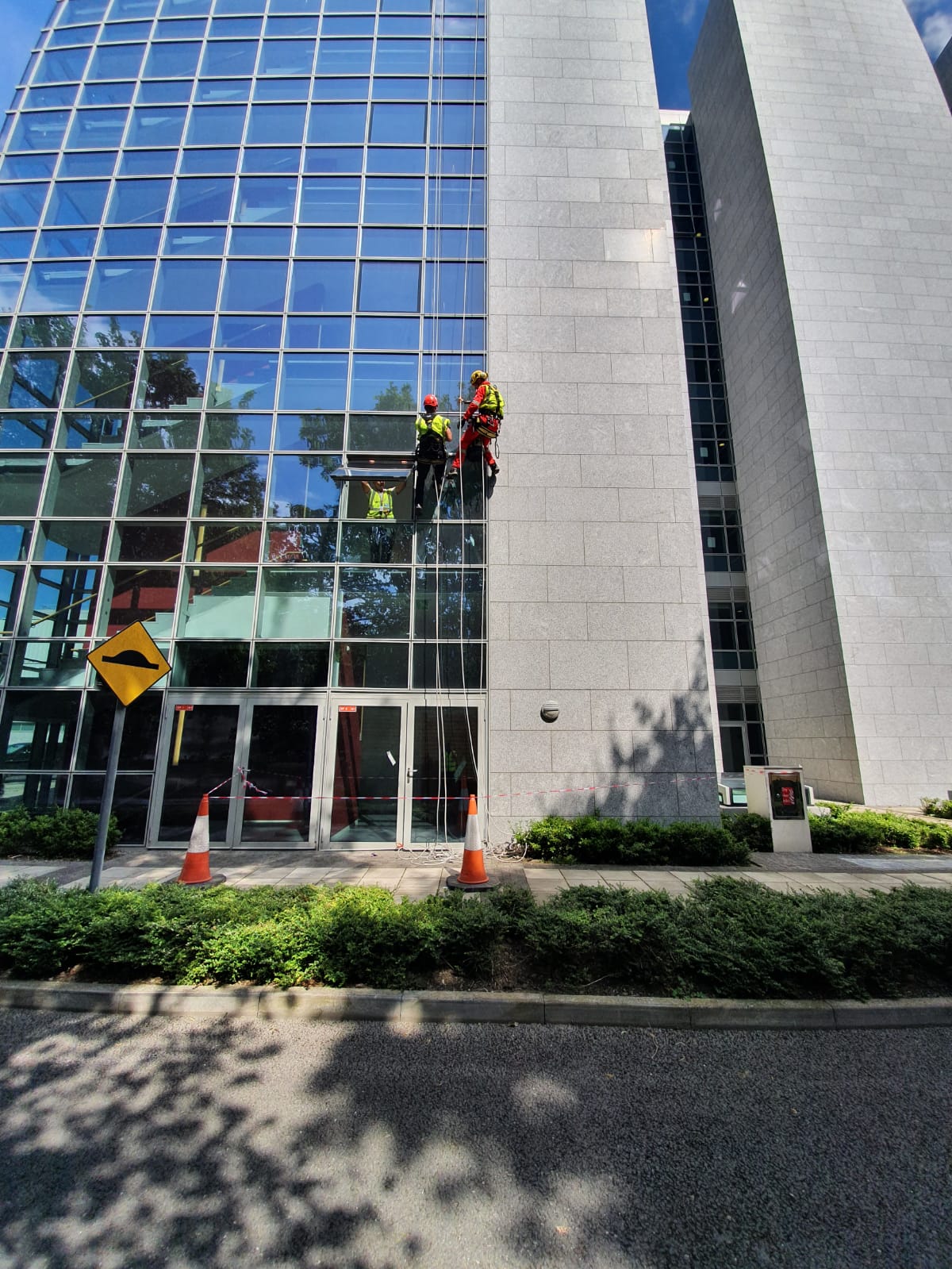 Two men are cleaning the windows of a tall building.