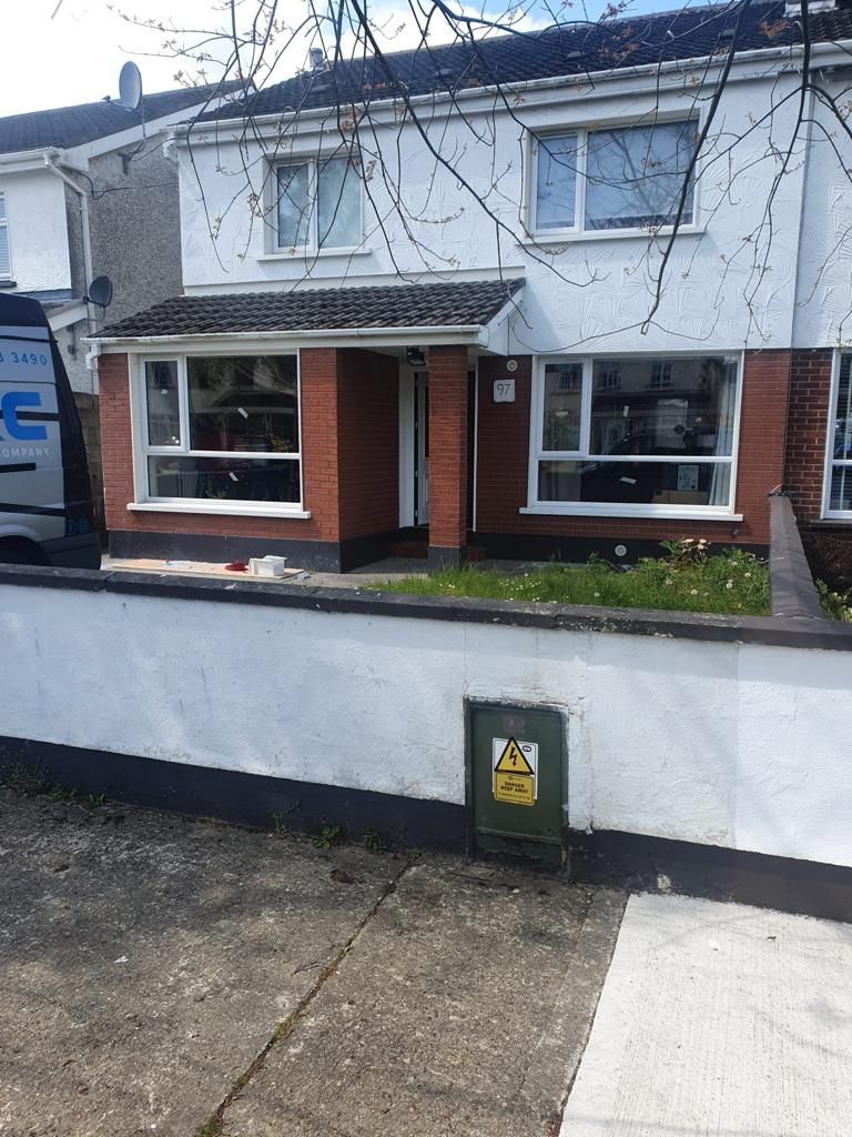 A white van is parked in front of a brick house.