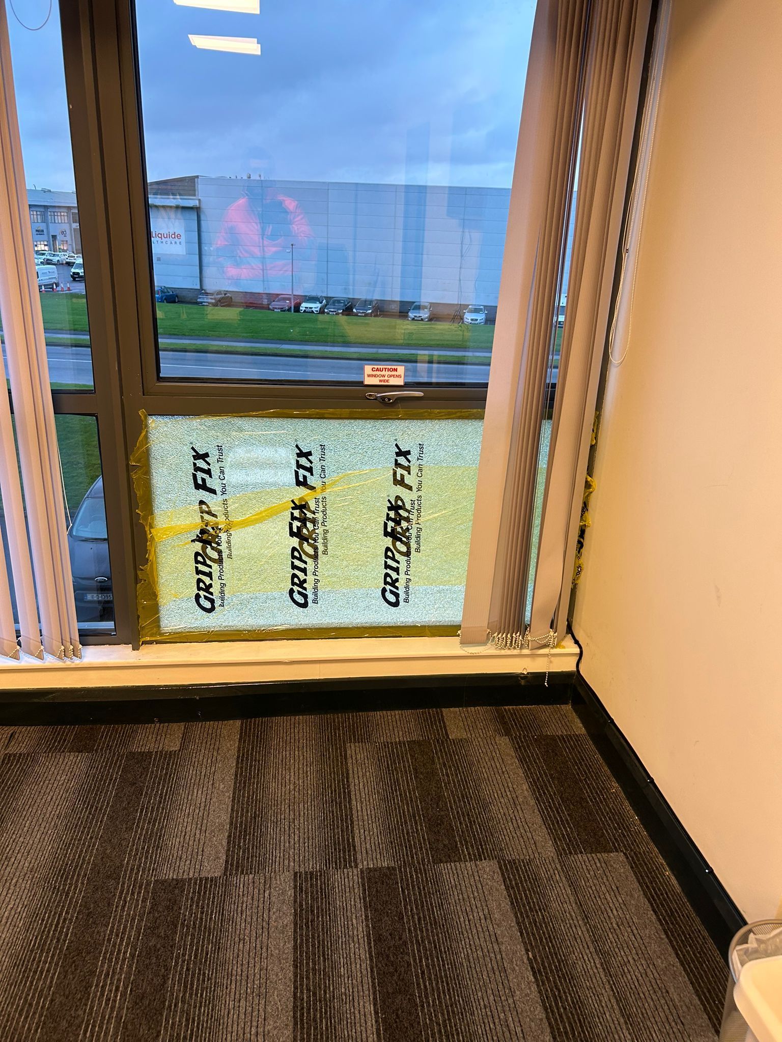 A room with a large window and a carpeted floor.