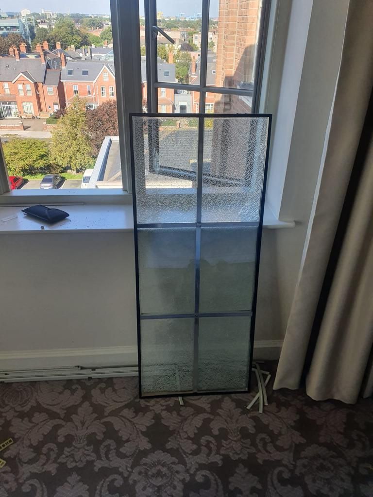 A glass window is sitting on a window sill in a room.