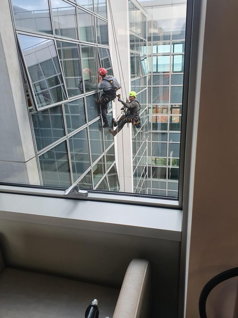 Two men are cleaning the windows of a tall building.