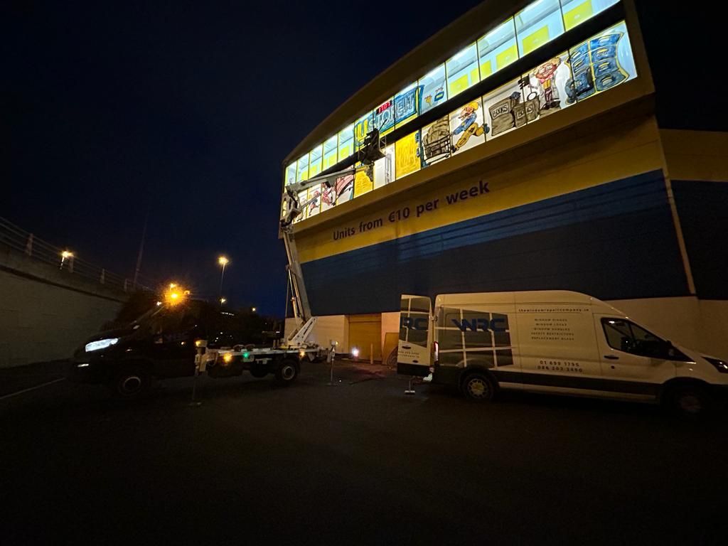 Two vans are parked in front of a building at night.