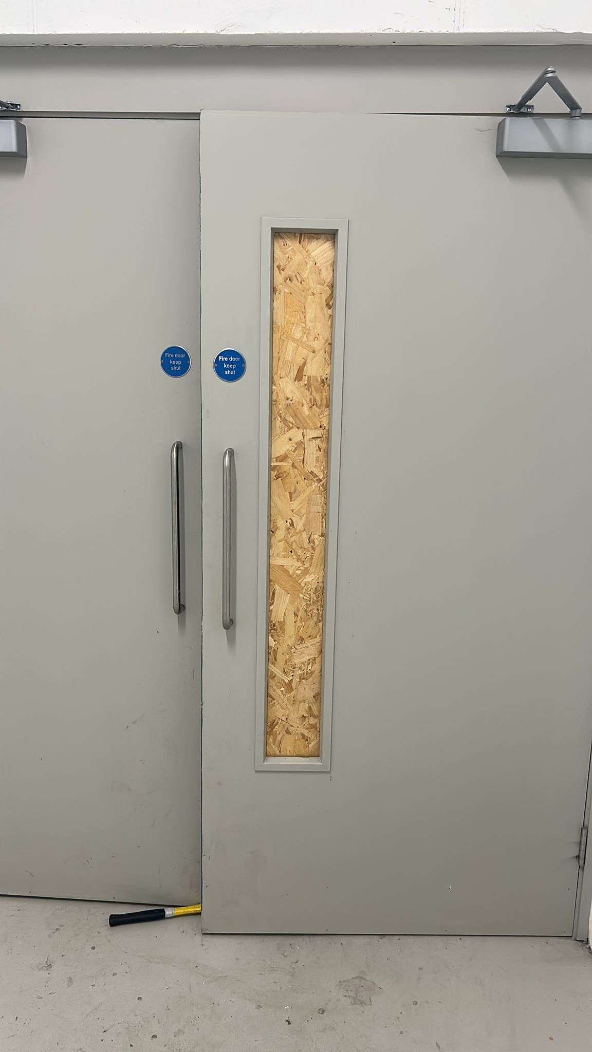 A sliding door with a window and a piece of plywood on it.