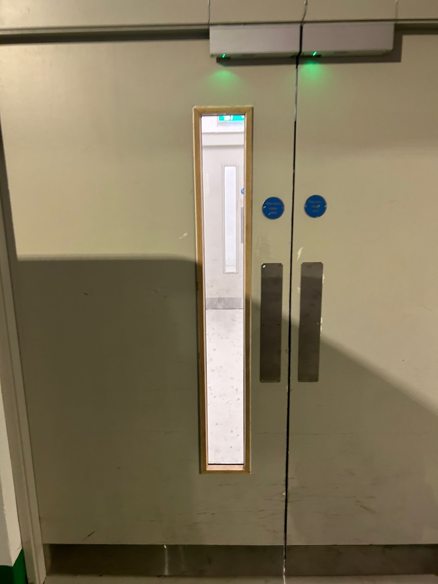 A door with a window and a green light on it