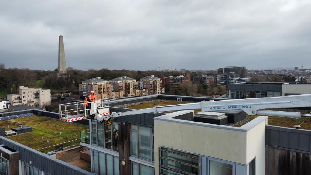 An aerial view of a building with a green roof and a tower in the background.