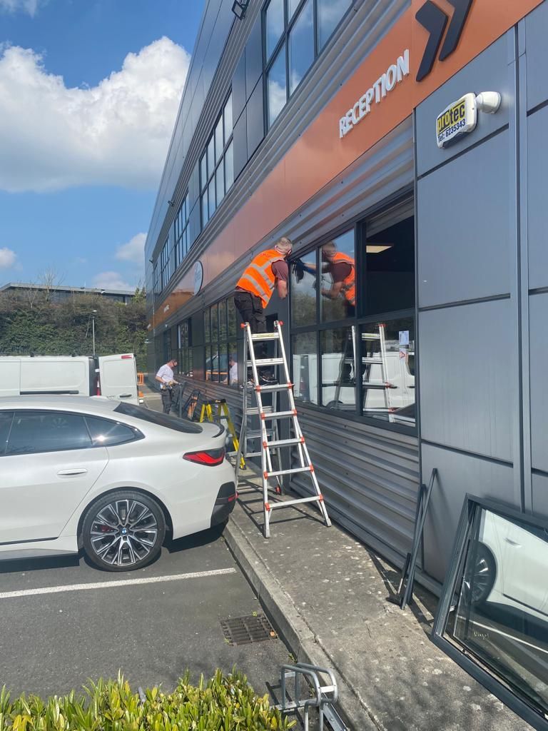 A white car is parked in front of a building that says reception