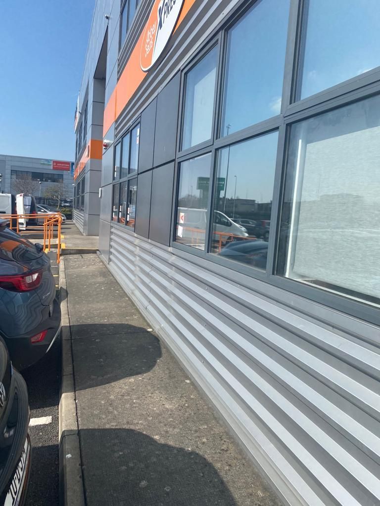 A car is parked in front of a building with a lot of windows.