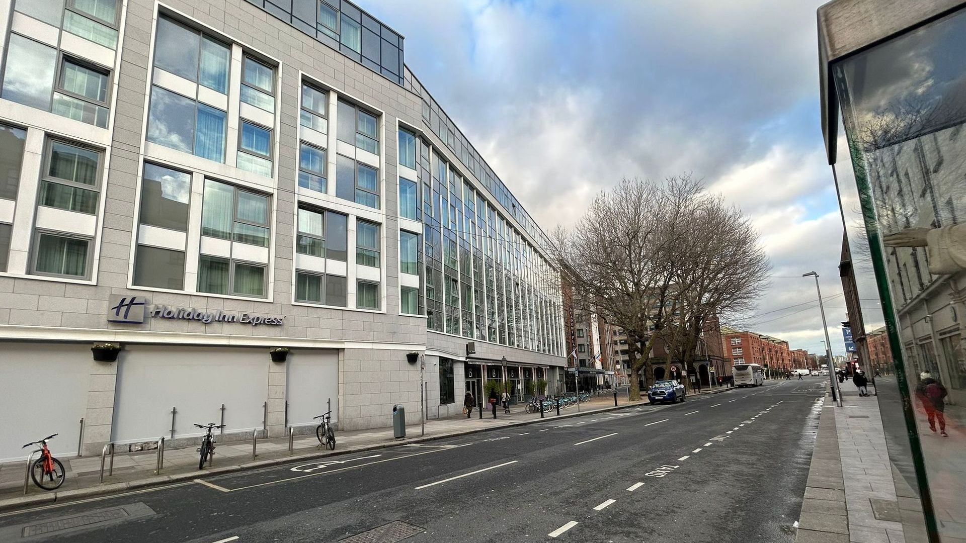 A large building with a lot of windows is on the side of a city street.