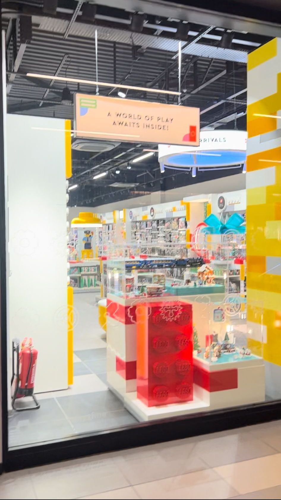 The inside of a store with a large window and a sign hanging from the ceiling.