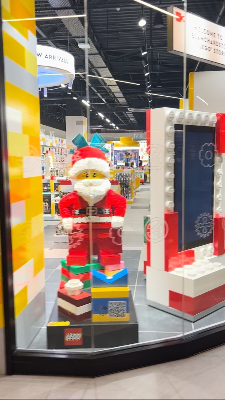 A lego santa claus statue is in a store window.