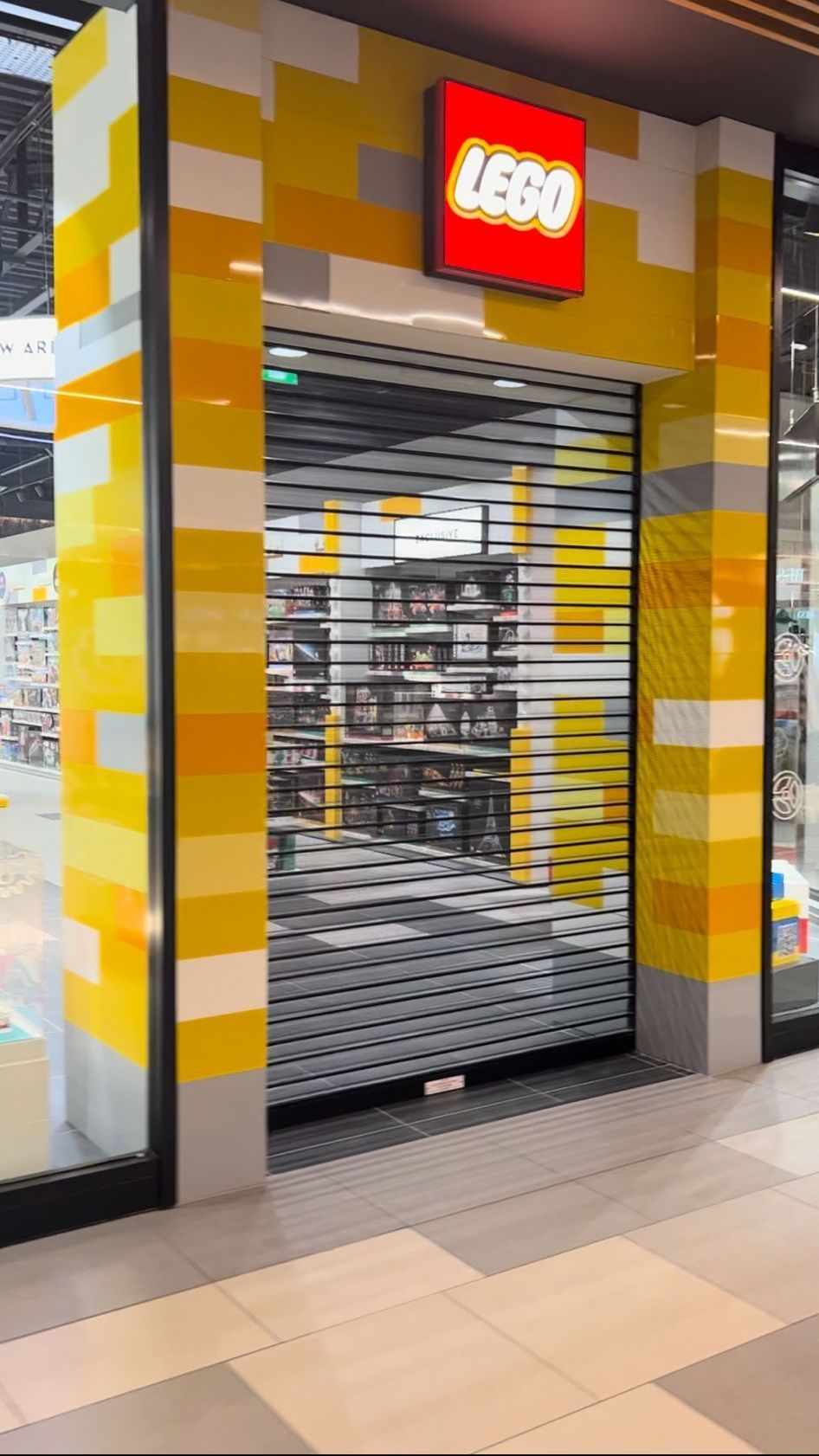 A lego store is closed and has a rolling shutter on the door.