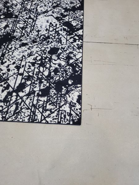 A Black and White Rug on a Concrete Floor