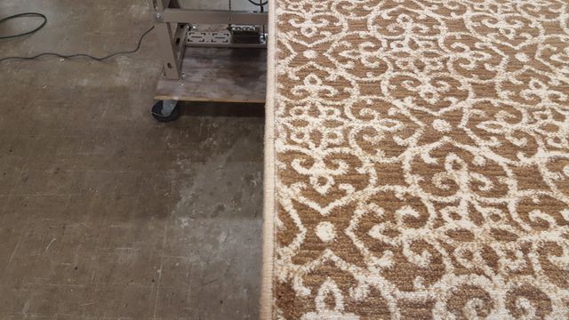 A Brown and White Rug is Sitting on a Concrete Floor Next to a Cart