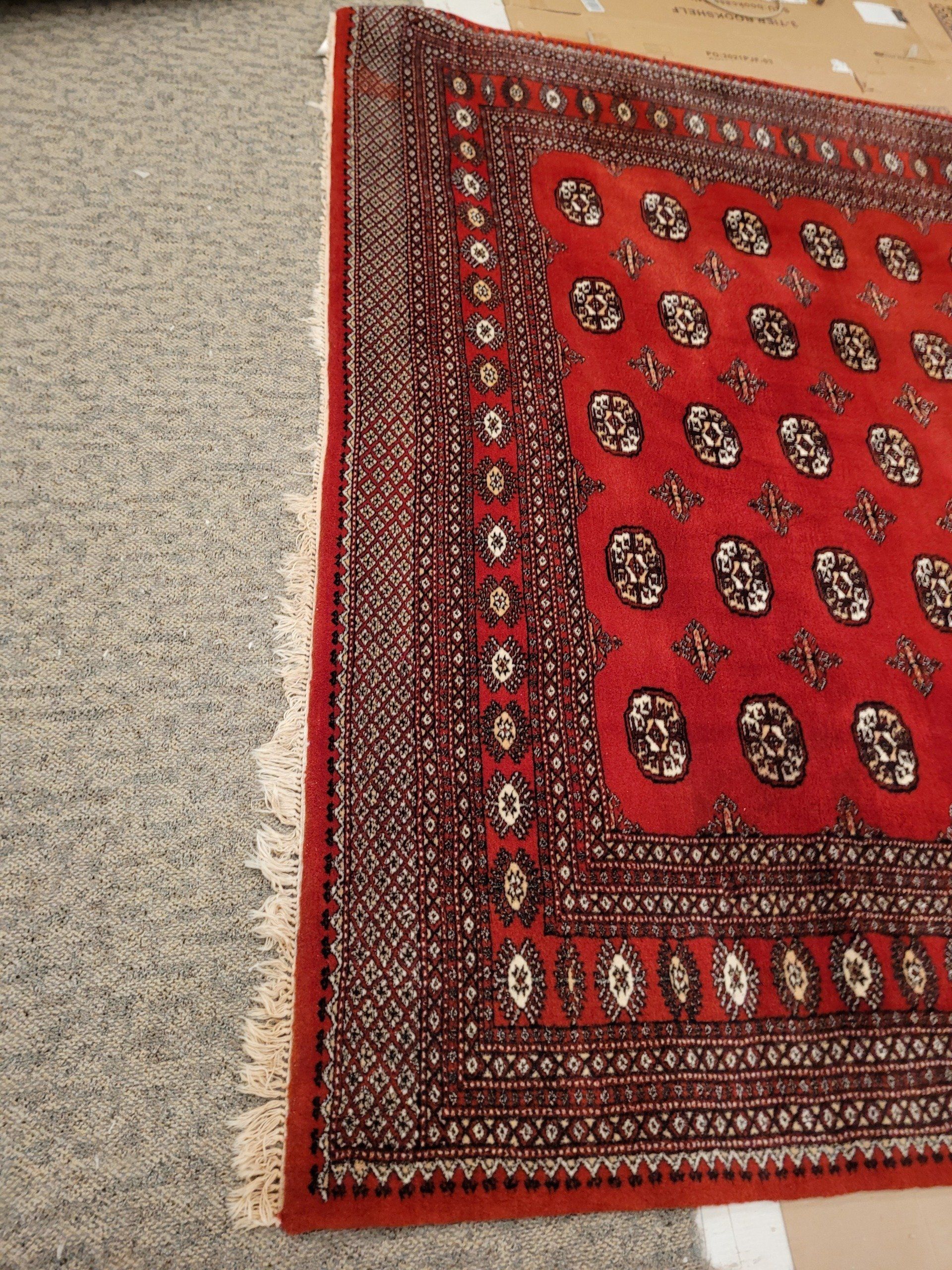 A Red Rug is Sitting on a Gray Carpet