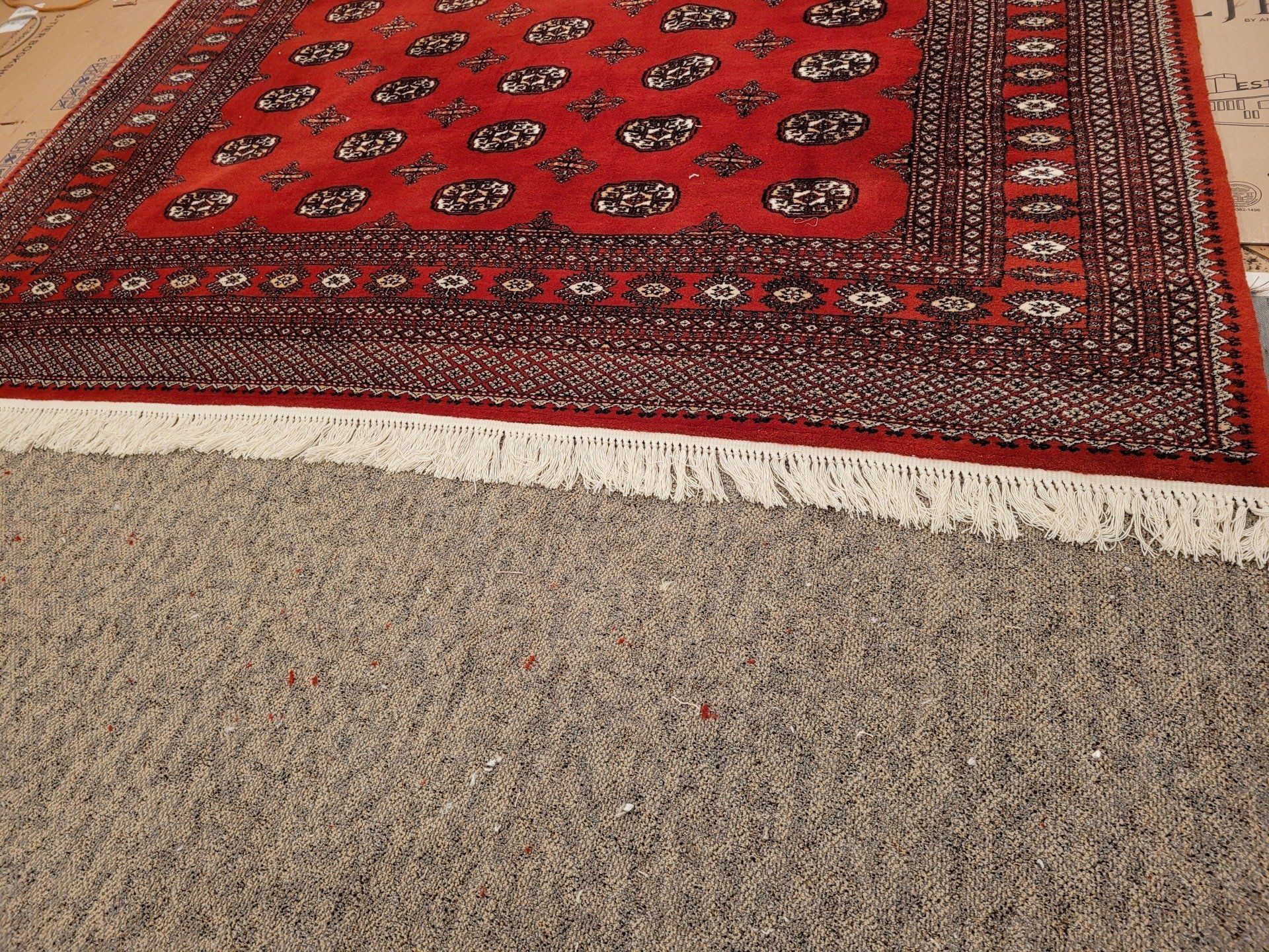 A Red Rug is Sitting on Top of a Gray Carpet