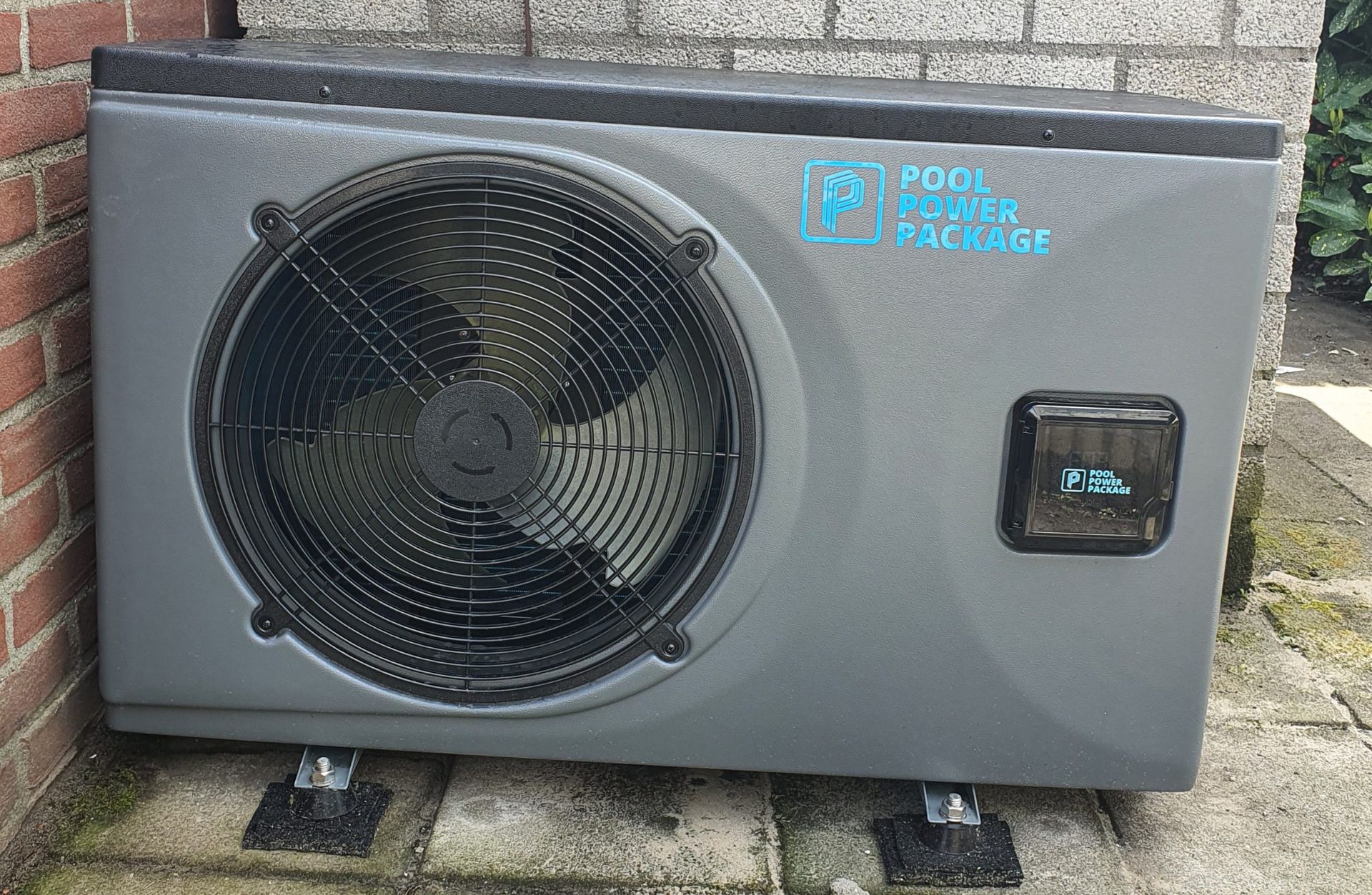 Een grote ventilator staat naast een stenen muur.