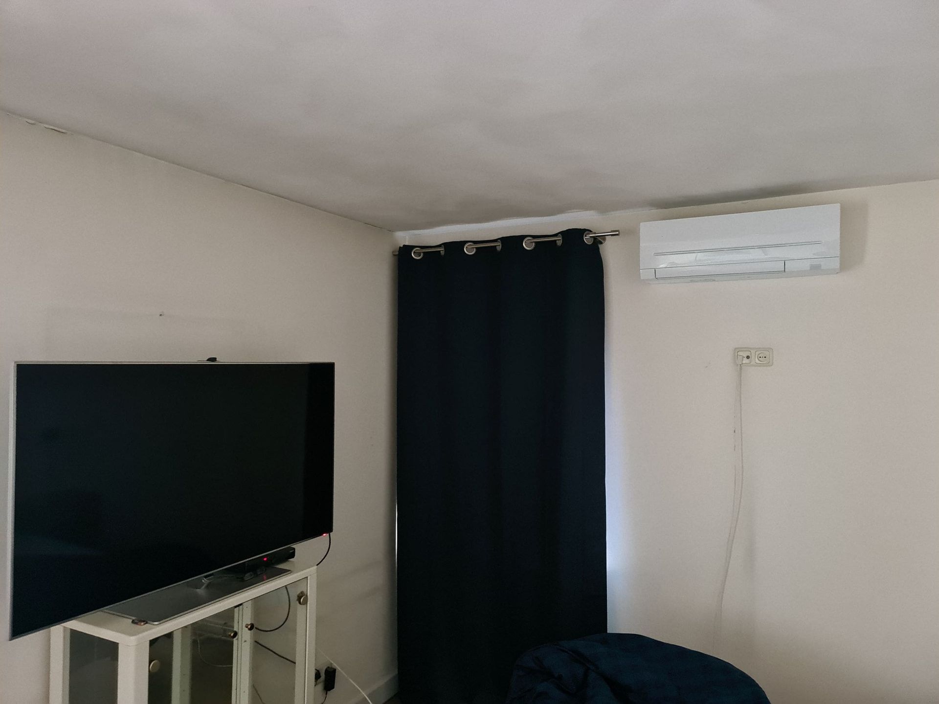 Een woonkamer met een flatscreen-tv en airconditioning.