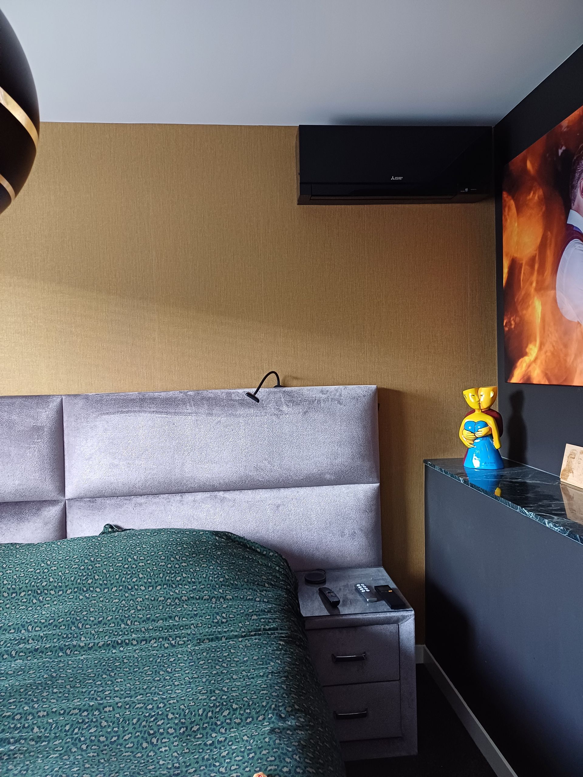 Zwarte Mitsubishi Electric Design airco boven het bed in een stijlvol ingerichte slaapkamer.