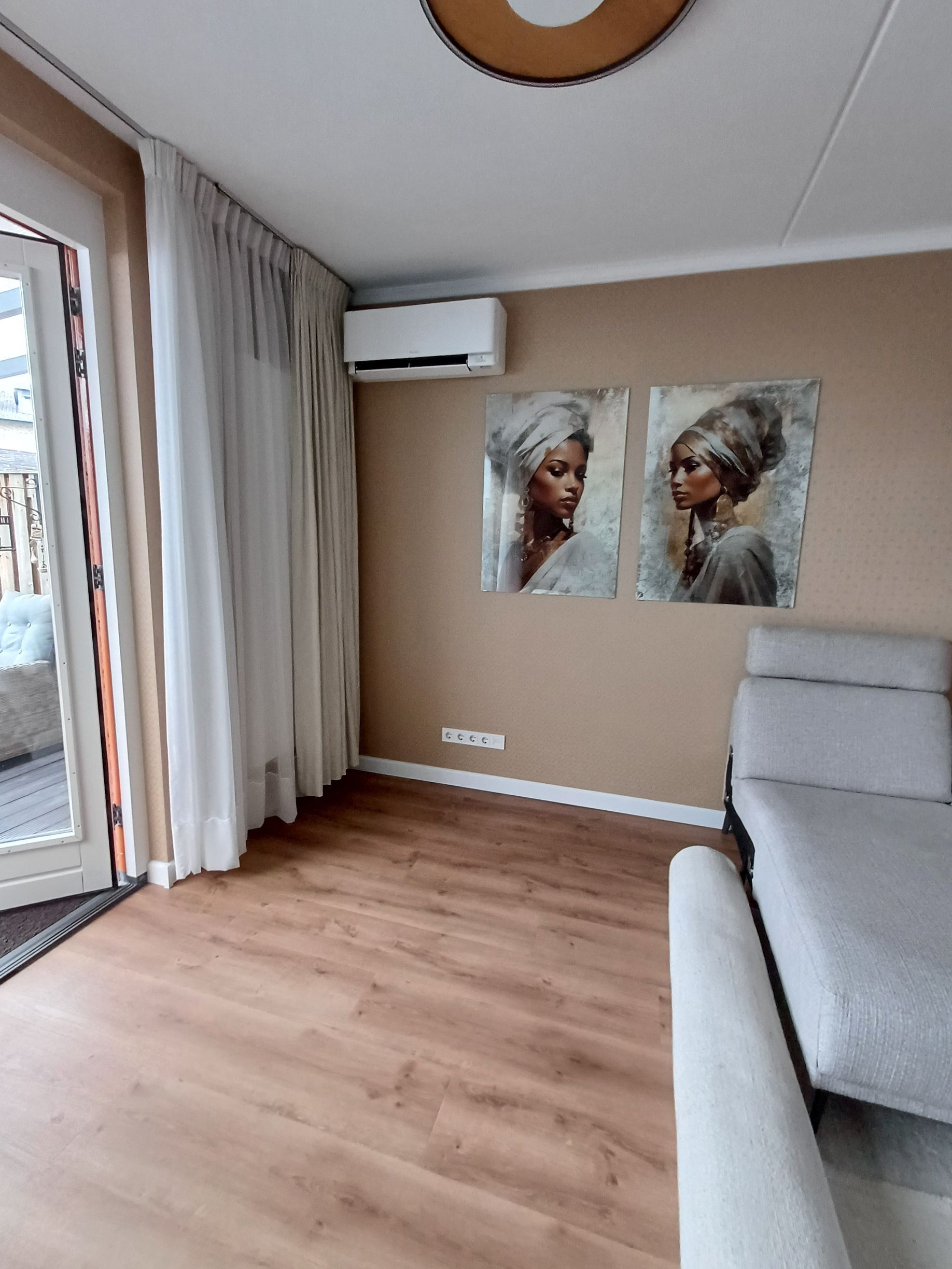Daikin Perfera wandmodel airco gemonteerd in een moderne slaapkamer met grijze muren, naast een raam met uitzicht op een groene tuin