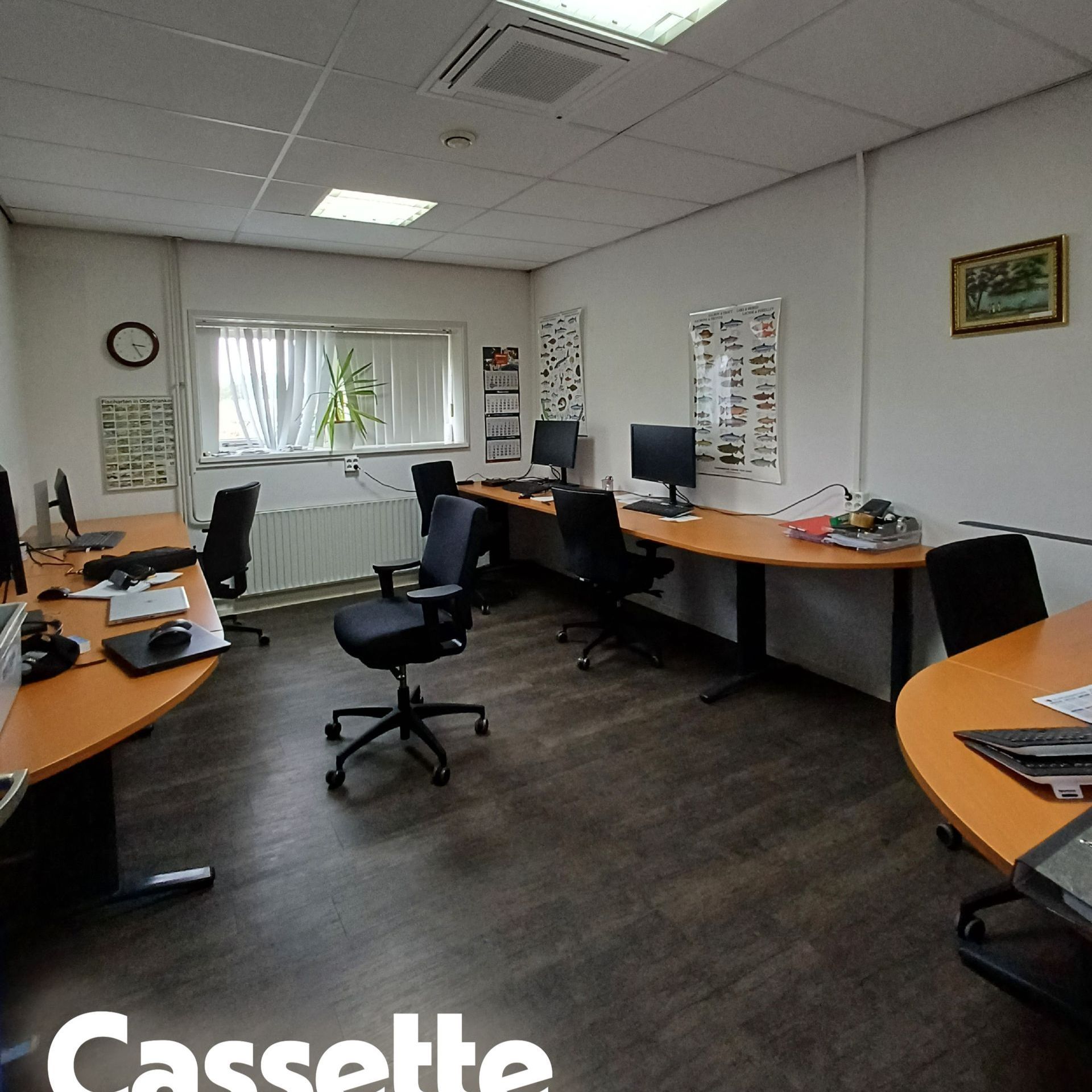 Kantoorruimte met systeemplafond waarin een cassette airco is geïnstalleerd, zichtbaar boven het bureau met computer en documenten.