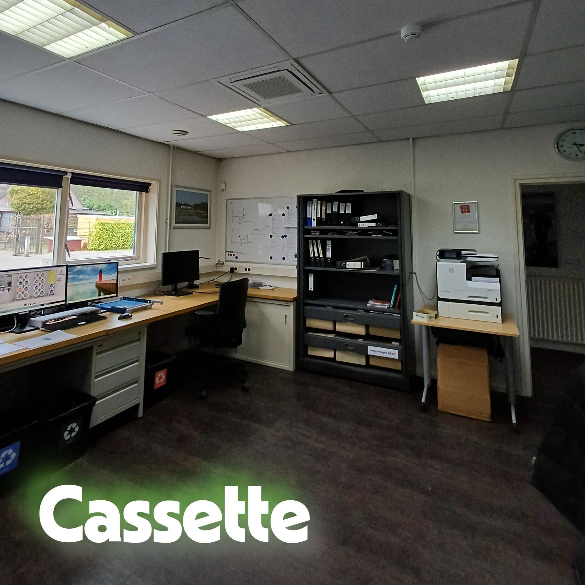 Kantoorruimte met systeemplafond waarin een cassette airco is geïnstalleerd, zichtbaar boven het bureau met computer en documenten.