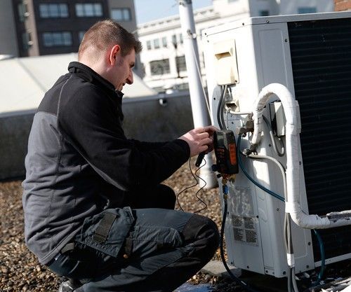 Een man werkt aan een airconditioner op een dak