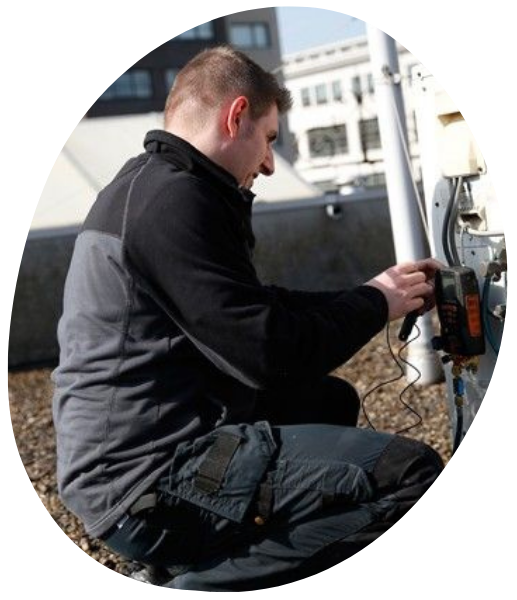 Een man in een zwart-grijs jasje werkt aan een apparaat