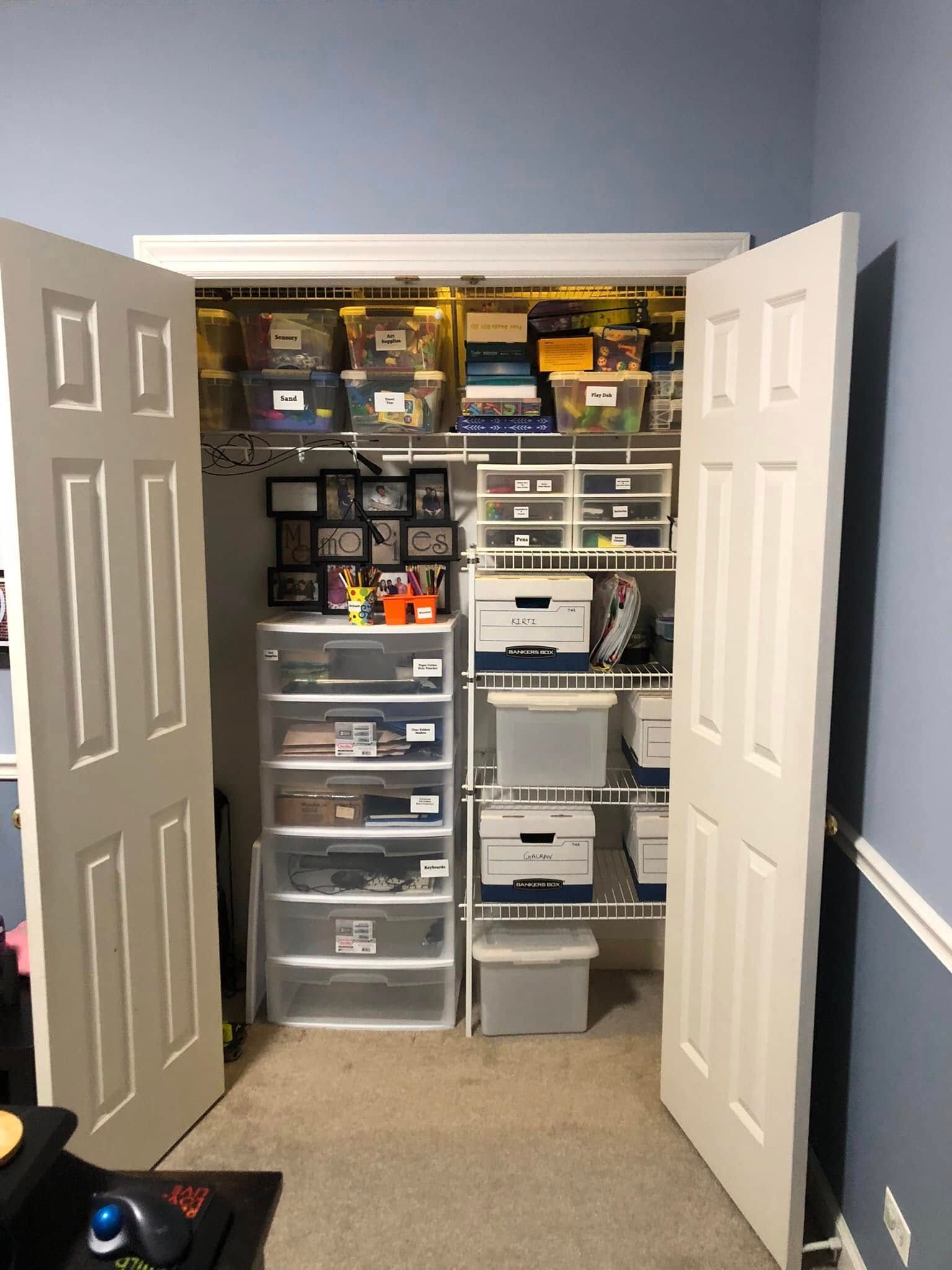 A closet with white doors and shelves filled with bins and storage containers.