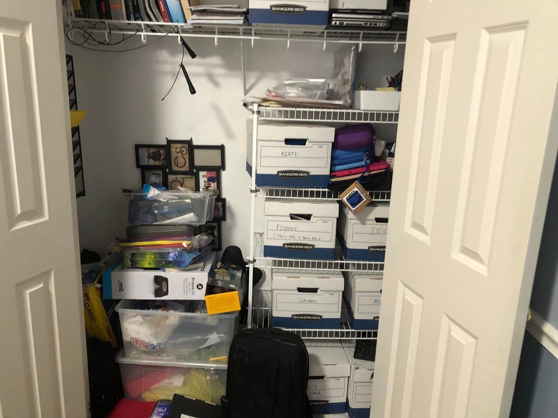 A cluttered white closet with boxes and shelves, visible through partially open white doors.