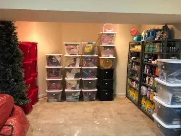 Basement storage with bins and shelves stacked against beige walls.
