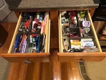 Two open wooden drawers with organized items in gray dividers.
