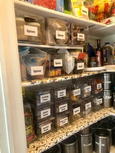 Organized pantry shelves with clear bins containing labeled spices and food items.