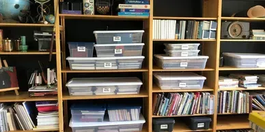 Wooden bookcase filled with books, storage bins, and decorative items.