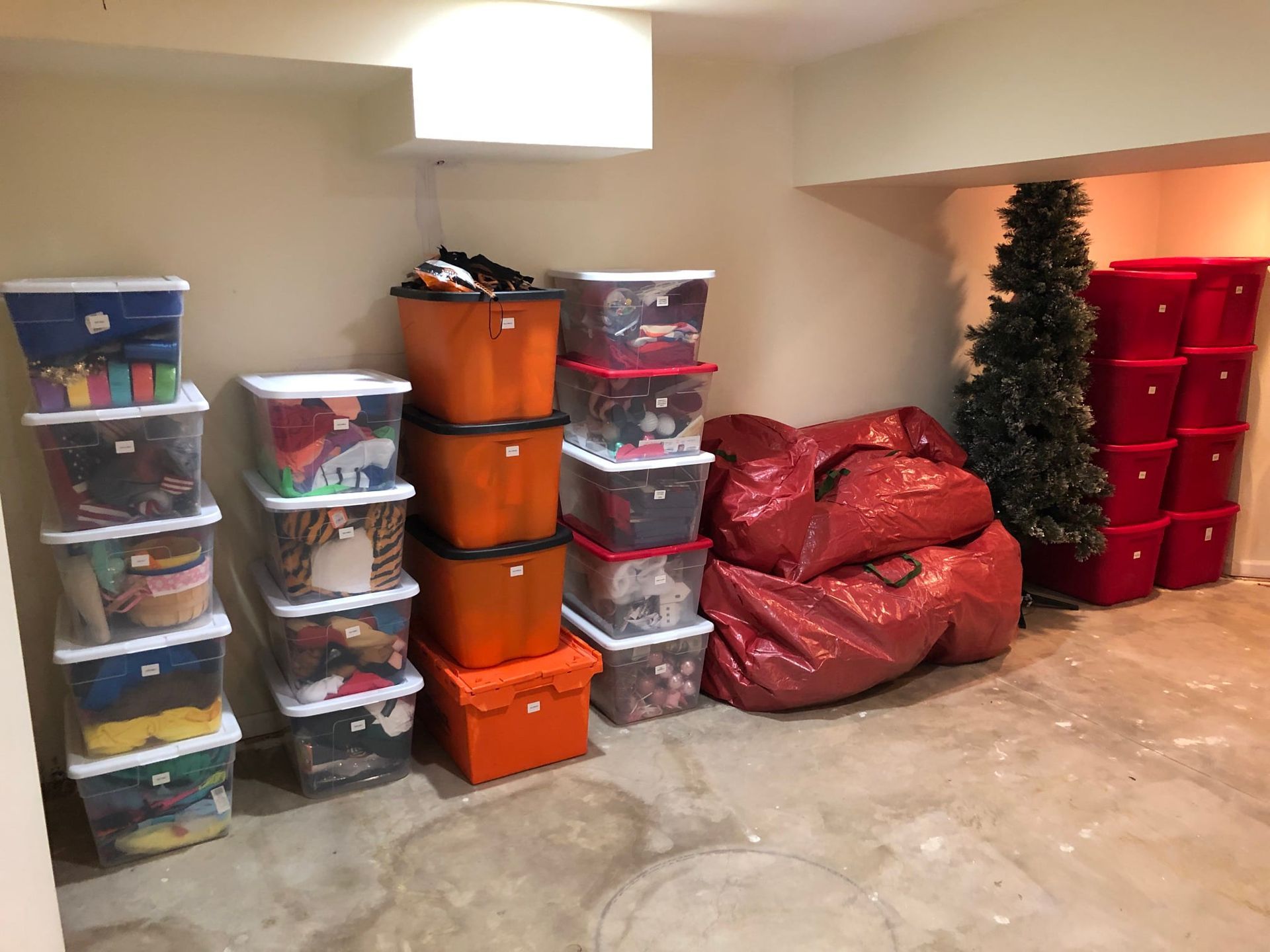 Basement storage with stacked plastic bins and bags filled with items.